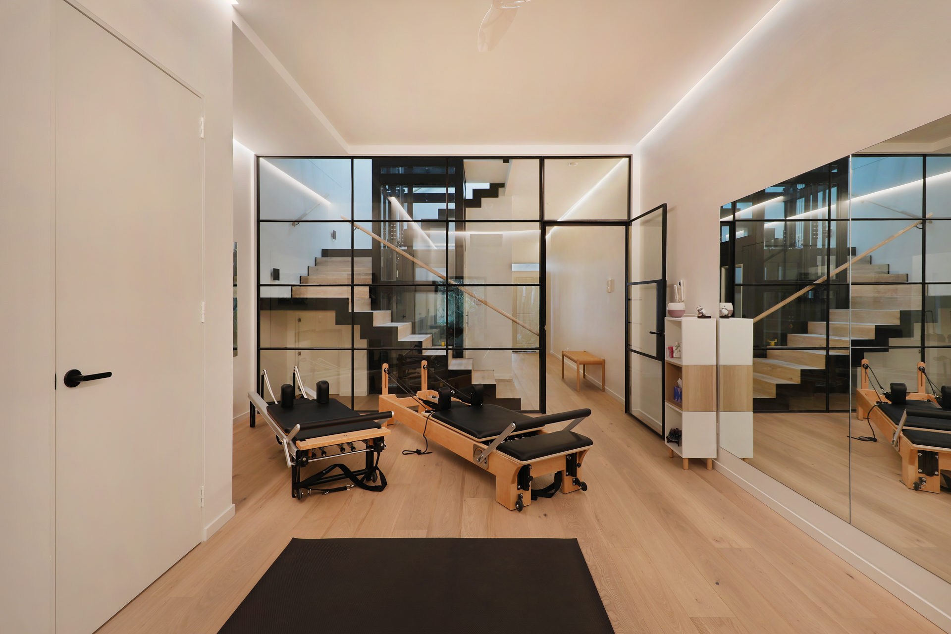 Pilates studio viewed through black steel-framed glass partition from staircase, George Street Fitzroy — Eco Building Design