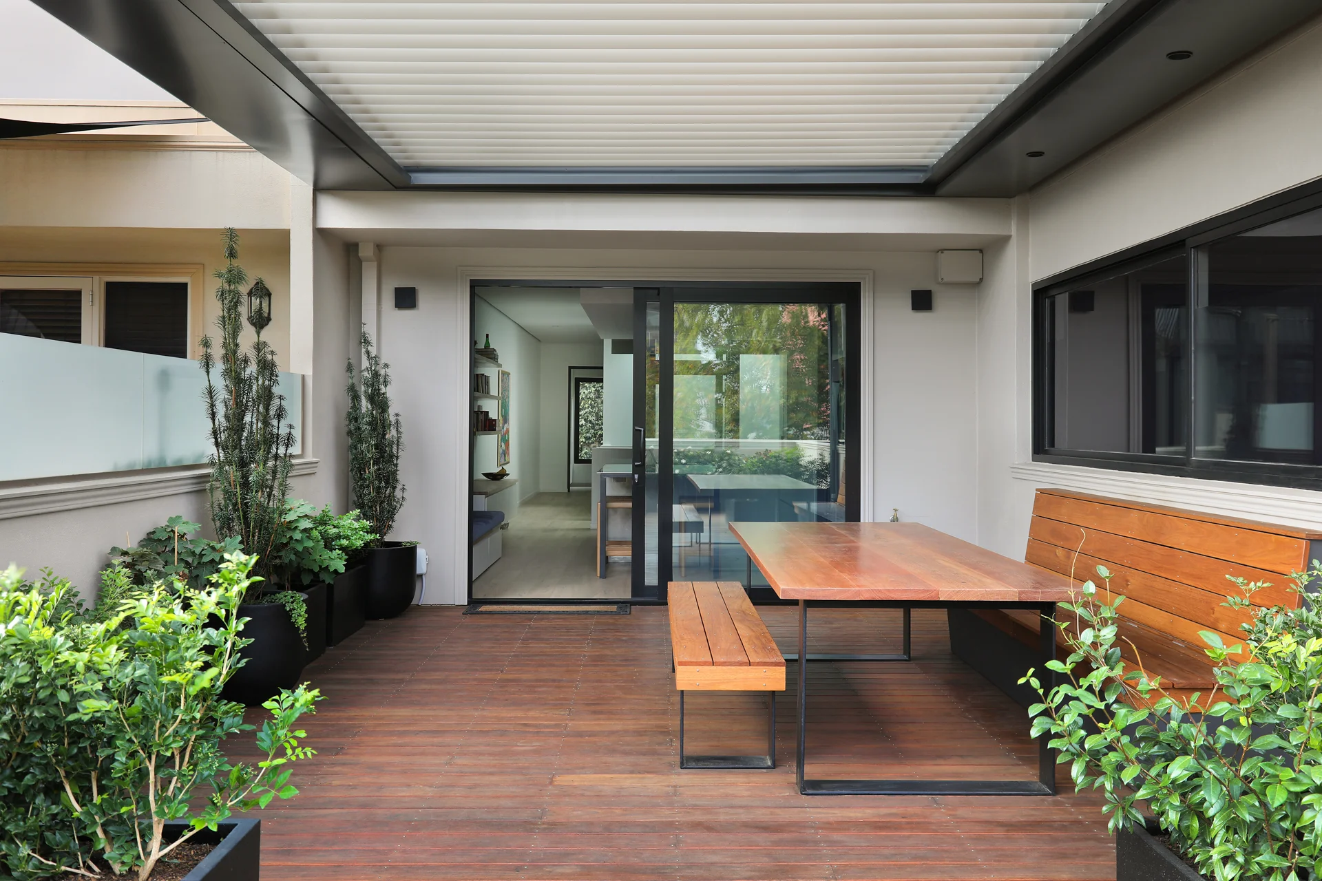 Rooftop terrace with reclaimed timber furniture, under an adjustable louvered pergola, George Street Fitzroy