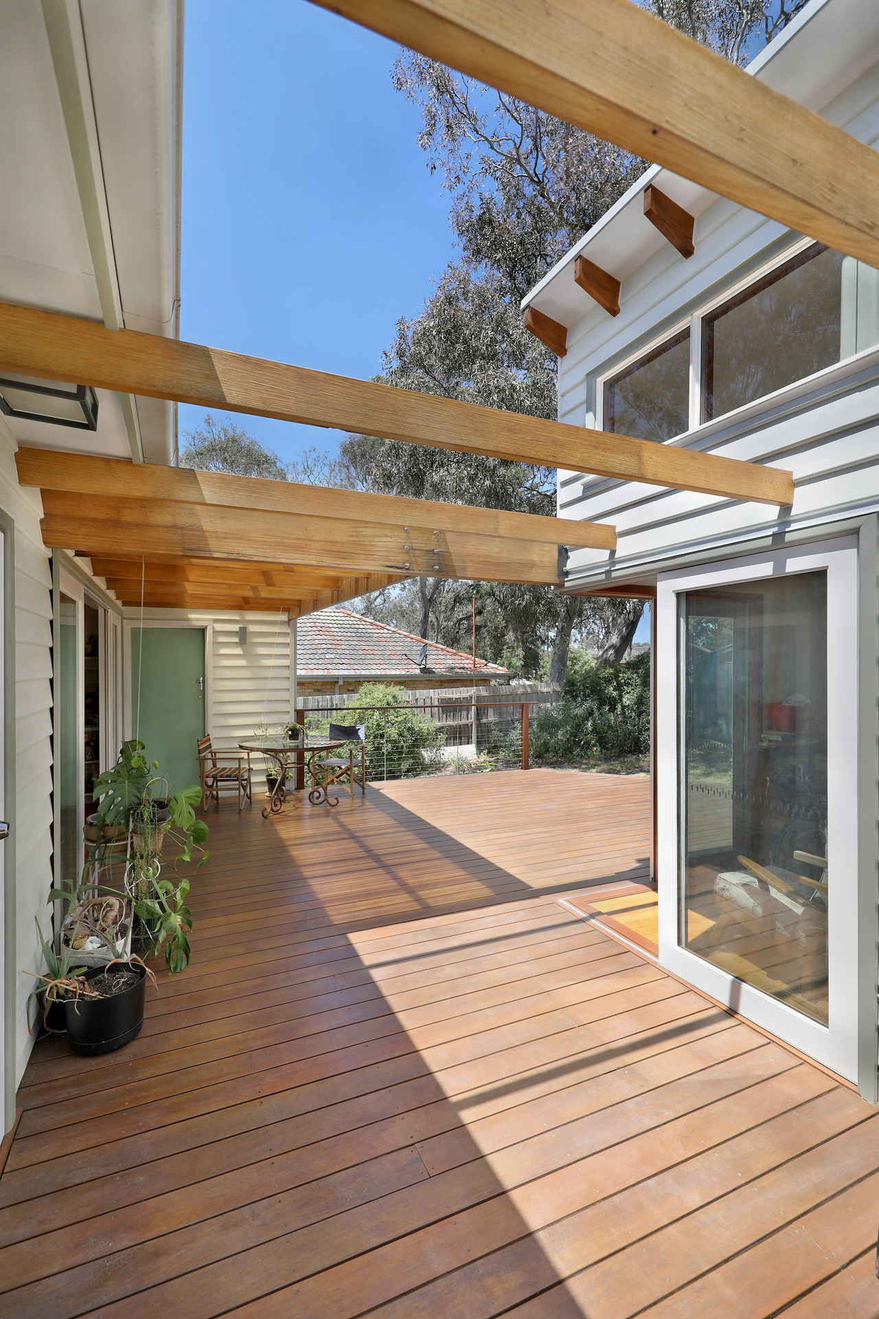Tall pergola beams and timber deck glowing in raking sunlight, Joynt Street Macleod