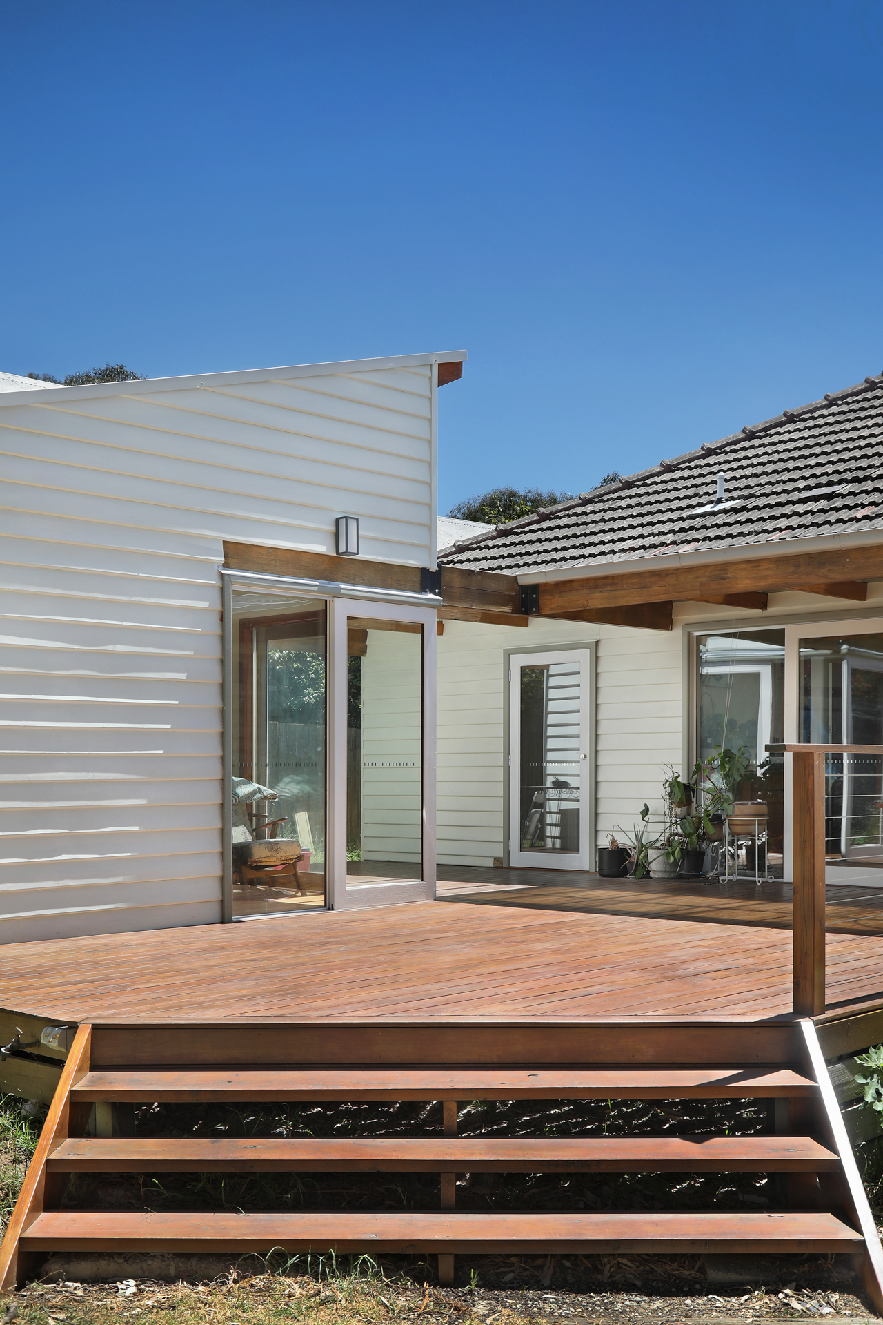 Timber deck and steps of the modern rear addition under a deep blue sky, Joynt Street Macleod